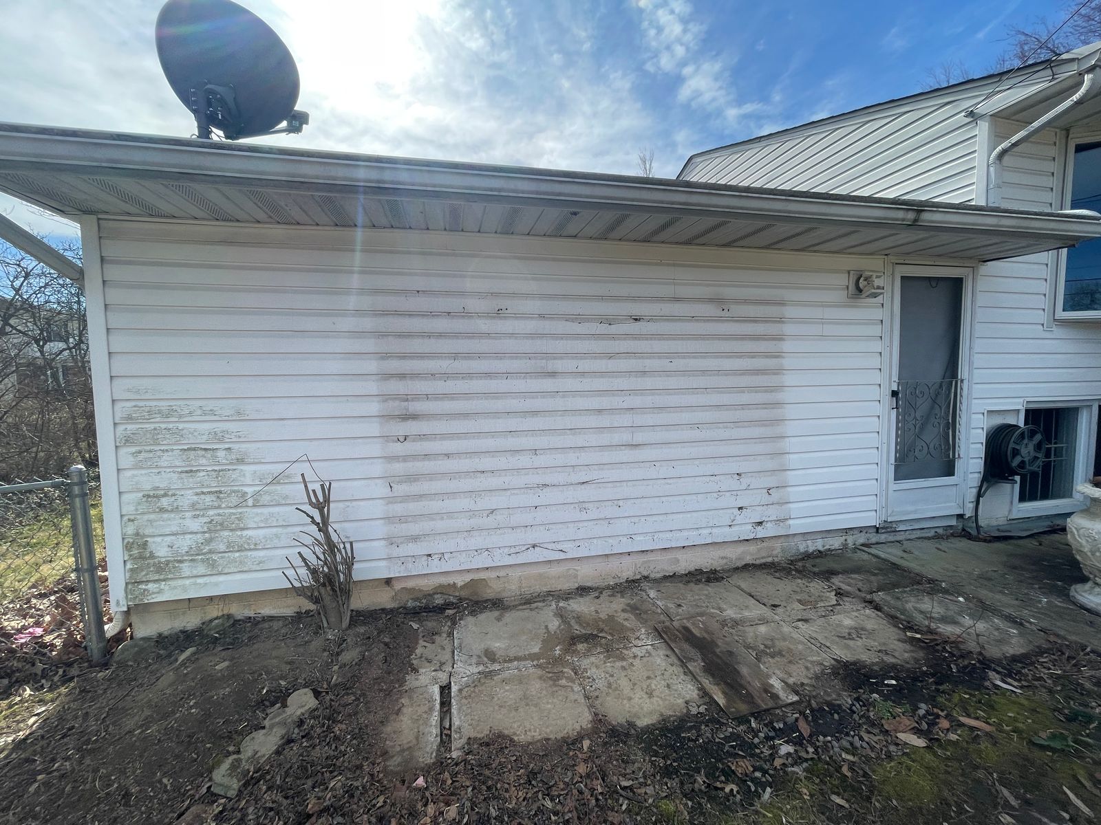 White vinyl siding half-washed, clean line against the grime